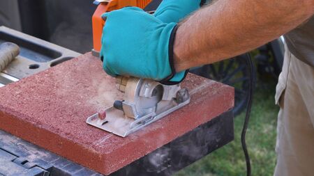 Tile cutter industry equipment. Worker cutting paving tiles for laying on the terrace using circular...