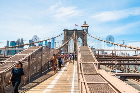 New York City/USA - May 26, 2019  Brooklyn Bridge, NYC. Pedestrian path across Brooklyn Bridge. Walking people, and Manhattan downtown with skyscrapers over East River on background.のeditorial素材