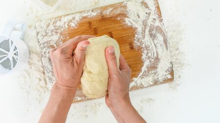 Dough preparation. Woman hands kneading dough in flour on a wooden board. Top view,white backgroundの写真素材