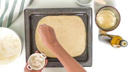 Baking cheese bread step by step. Topping bread dough with seasoning salt. Close up, top view, on white background.の写真素材