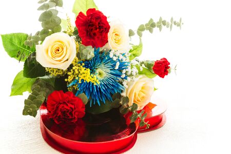 Bouquet of beautiful flowers and candy box close up on white background with copy spaceの写真素材