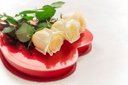 White roses and candy box. Bouquet of gorgeous white roses and red present candy box close up on white background with copy spaceの写真素材