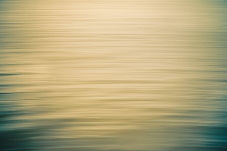 Sunset over the ocean abstract background. Water surface, soft yellow and turquoise colors, motion blur, play of ripplesの写真素材