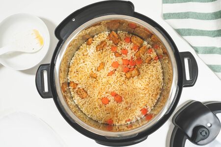 Rice with meat and vegetables prepared in multi cooker, close up on white background, view from aboveの写真素材
