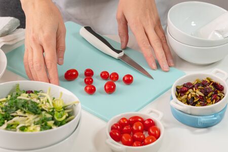 Woman preparing vegetable salad. Close up of fresh organic vegetables, cabbage mix, tomatoes, dried...