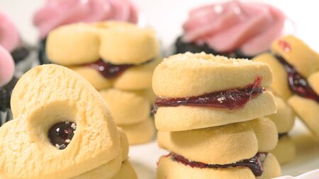 Chocolate cupcakes with raspberry buttercream frosting, and heart shaped cookies close up on white background, top view.の写真素材