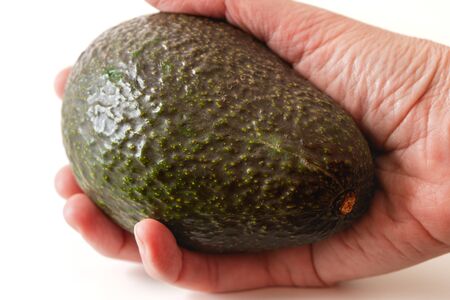 Avocado in hand close up on white backgroundの写真素材