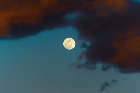 Abstract landscape. Dramatic night sky. Dark red clouds, and bright Moonの写真素材