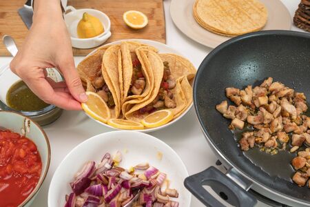 Chicken tacos and some ingredients close up on a kitchen table. Woman prepares tacos, view from aboveの写真素材