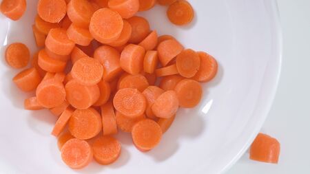 Chopped carrot on a plate, close up on white background, view from aboveの写真素材