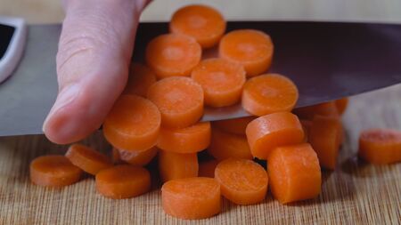 Chopping carrot on  a wooden chopping board, close upの写真素材