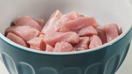 Chopped raw pork meat in a bowl - ready for cooking. Close up on white backgroundの写真素材