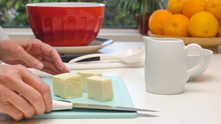 Stick of butter on a cutting board. Woman cuts butterの写真素材