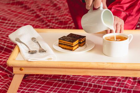 Cup of coffee with milk, and chocolate cake. Sweet delicious breakfast on a bed tray tableの写真素材