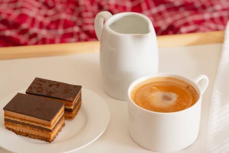 Cup of coffee with milk, and chocolate cake. Sweet delicious breakfast on a bed tray tableの写真素材