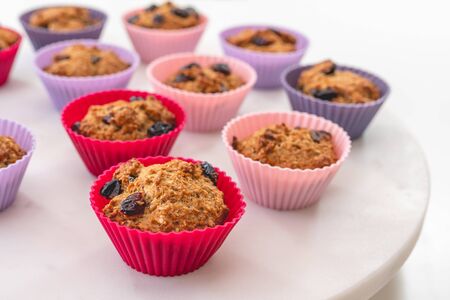 Bran muffins with dry cranberries close up in baking silicon cups on white background. Healthy food, good source of dietary fiberの写真素材