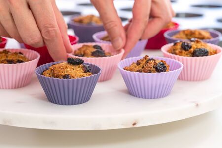 Bran muffins with dry cranberries close up in baking silicon cups on white background. Healthy food, good source of dietary fiberの写真素材