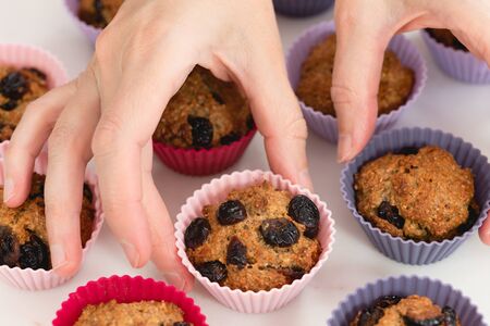 Bran muffins with dry cranberries close up in baking silicon cups on white background. Healthy food, good source of dietary fiberの写真素材