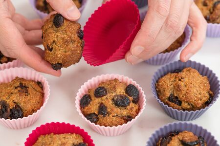 Bran muffins with dry cranberries close up in baking silicon cups on white background. Healthy food, good source of dietary fiberの写真素材