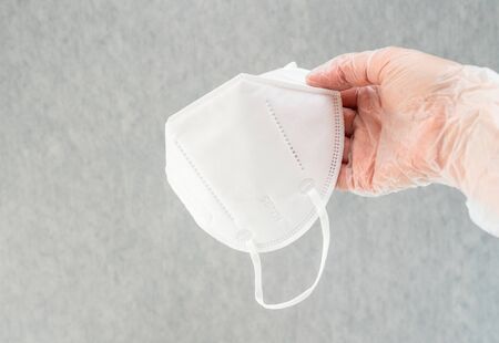 Female hands wearing vinyl gloves  holding KN-95 protection face masks. Close up shot, copy space. ...