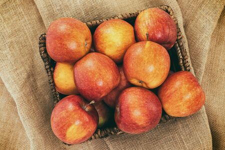 Fresh red apples in wicker basket on rustic background, close up, view from aboveの写真素材