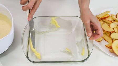Biscuit batter preparation process. Woman spreads butter and flour over the sides of glass baking form.の写真素材