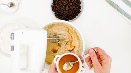 Chocolate Chip Cookies recipe. Chef adds few teaspoon vanilla extract into a cookie batter, close up...