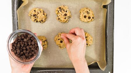 Chocolate Chip Cookies recipe. Woman placing chocolate chips on the top of unbaked cookies, close up, view from aboveの写真素材