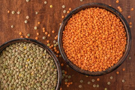 Red lentils and green lentils close up in a bowls on wooden background, view from aboveの写真素材