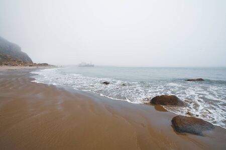 Sand beach and Morro Rock at overcast day, Californiaの写真素材