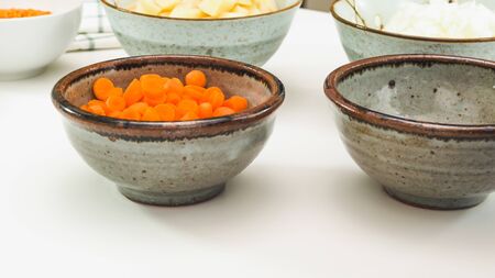 Chopped carrot in a bowl close up on white kitchen tableの写真素材