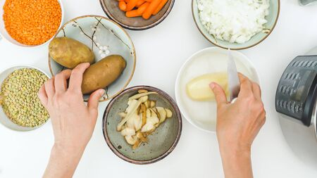 Peeling potatoes. Lentil soup recipe. Ingredients for cooking needs close up on kitchen table, view from aboveの写真素材