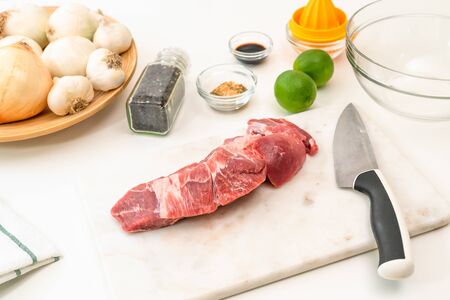Fresh raw pork meat and ingredients for marinade close up on white kitchen tableの写真素材