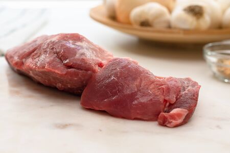 Fresh raw pork meat and some ingredients for marinade close up on a marble board on white backgroundの写真素材