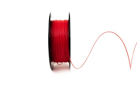 3D Printer Plastic Filament. Spool of red thermoplastic wire for 3d printing close up isolated on white backgroundの写真素材