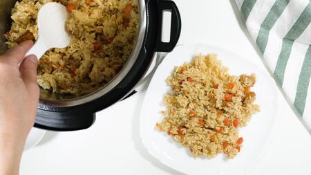 Rice, vegetables, and meat in a pot and on a plate. Cooking rice with meat and vegetables (or Rice Pilaf)  in pressure multi cooker step by step, top view.の写真素材