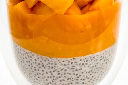 Chia seed layered pudding smoothie with mango close up in a glass on white backgroundの写真素材