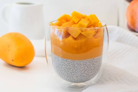 Mango Chia seed layered pudding smoothie close up on white background. Vegan healthy breakfast, dessertの写真素材