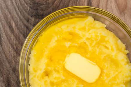 Mushed potato with melting butter close up in a glass bowl on wooden backgroundの写真素材
