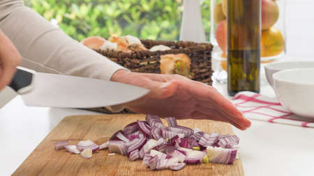 Chopped fresh red onion close up on a wooden chopping board on a kitchen tableの写真素材