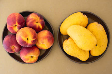 Peaches and mangoes on plates close up, view from aboveの写真素材