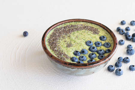 Bowl of celery banana smoothie with Chia seeds and fresh blueberries close up on white backgroundの写真素材