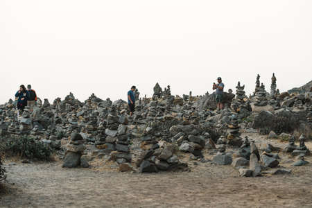 Morro Bay State Park, California - September 13, 2020.  People walking and taking pictures of stacked pebbles on the beach at sunsetのeditorial素材
