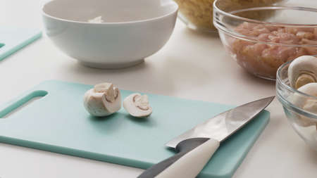 Fresh raw  chopped organic white mushrooms close up on cutting board on white backgroundの写真素材