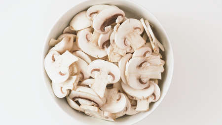 Bowl of fresh row chopped mushrooms close up on whiite background, flat layの写真素材