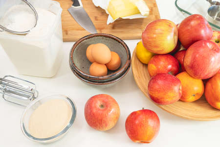 Baking apple pie. Apples, eggs, sugar, butter, flour, and some ingredients close up on a kitchen tableの写真素材