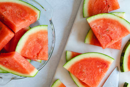 Watermelon slices on a plate and cutting board, close up view from aboveの写真素材
