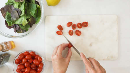 Chef cuts cherry tomatoes. Lettuce salad with tomatoes and honey mustard salad dressing recipe.の写真素材