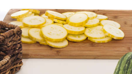 Zucchini slices closeup on wooden cutting board on white backgroundの写真素材
