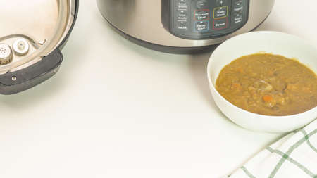 Creamy lentil soup cooked in multi cooker close up in a bowl on white background with copy spaceの写真素材